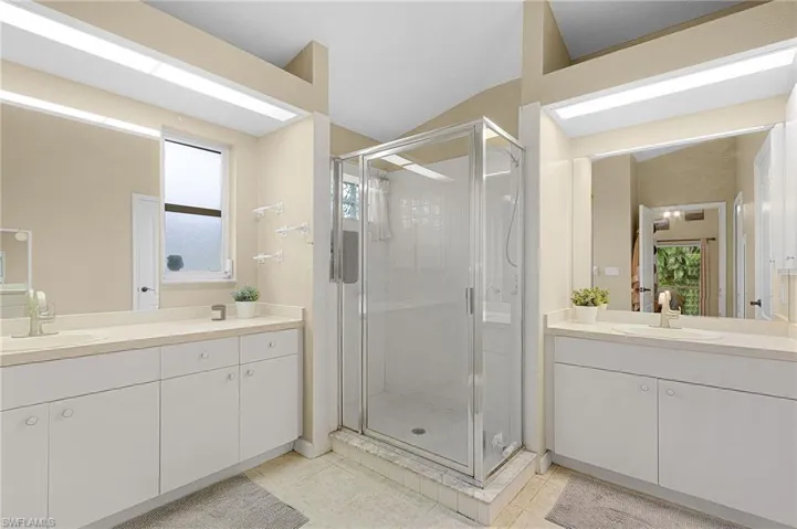 Bathroom with a shower stall, two vanities, and light tile patterned floors