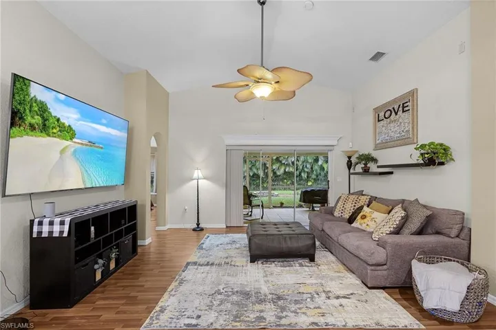 Living area featuring wood finished floors, arched walkways, ceiling fan, and high vaulted ceiling.