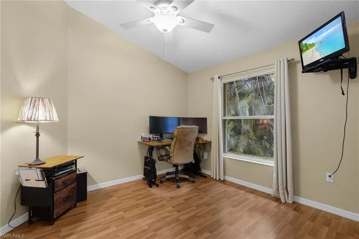 Home office or guest bedroom featuring lofted ceiling, light wood finished floors, and a ceiling fan