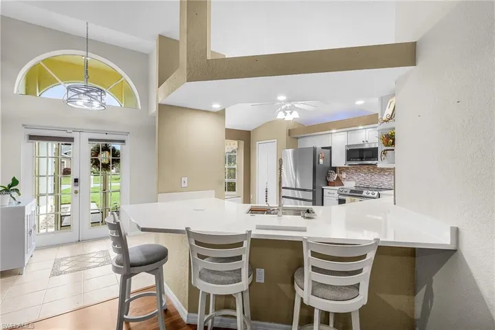 Kitchen featuring a kitchen bar, white shaker-style cabinets, newer stainless steel appliances, and a kitchen window bench/additional storage.