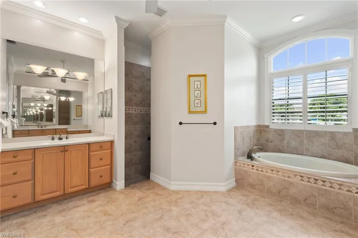 Bathroom featuring shower with separate bathtub, tile patterned floors, vanity, and crown molding