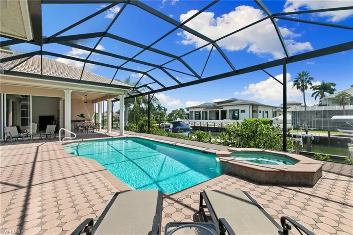 View of swimming pool with glass enclosure, an in ground hot tub, and a patio area