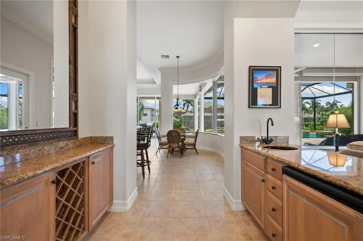 Kitchen with hanging light fixtures, stone countertops, light tile patterned floors, crown molding, and sink