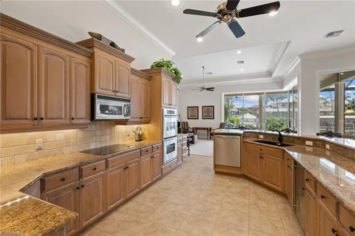 Kitchen with ceiling fan, sink, tasteful backsplash, appliances with stainless steel finishes, and light stone countertops