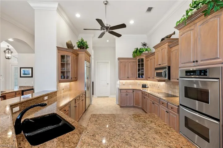 Kitchen with ceiling fan, ornamental molding, appliances with stainless steel finishes, and sink