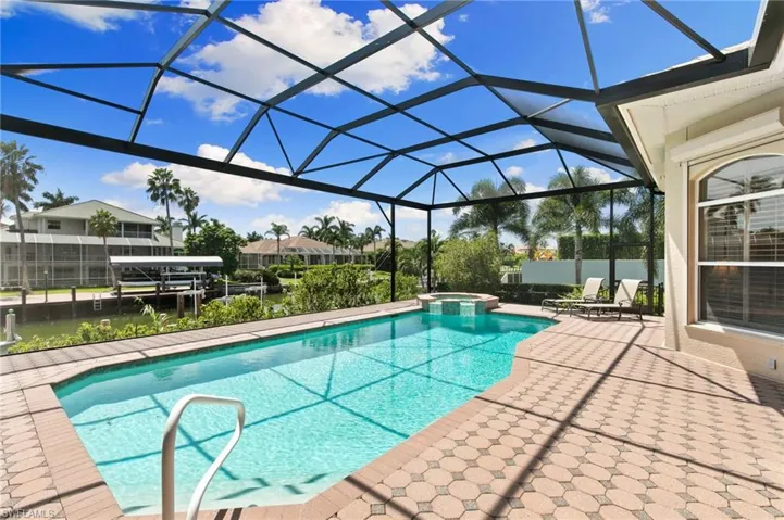 View of swimming pool with glass enclosure and a patio area