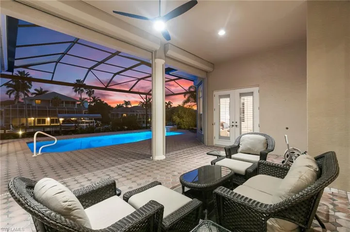 Patio terrace at dusk with a lanai, ceiling fan, and french doors
