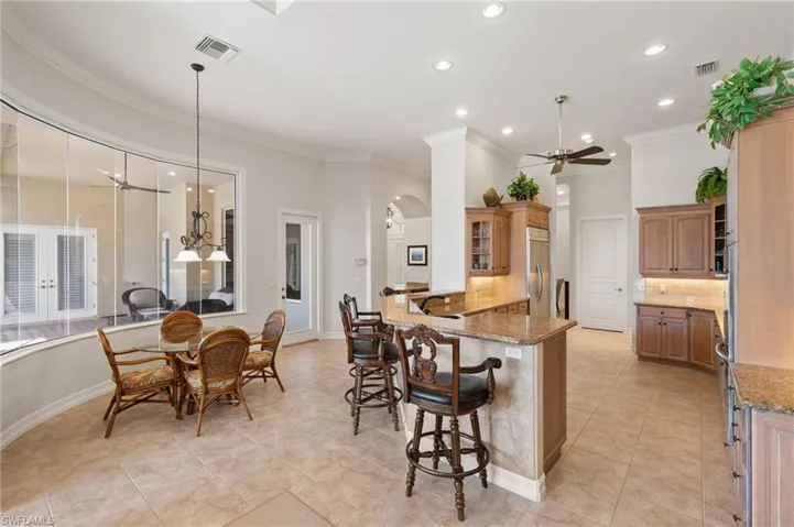 Kitchen featuring built in refrigerator, kitchen peninsula, pendant lighting, ceiling fan, and ornamental molding