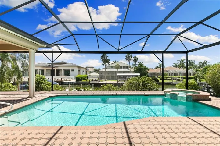 View of pool with glass enclosure, an in ground hot tub, and a patio area