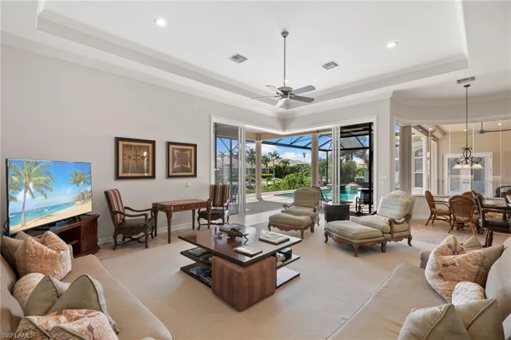 Living room featuring ceiling fan, light colored carpet, a raised ceiling, and crown molding