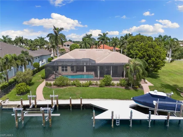 Rear view of property with a lanai, a yard, and a water view