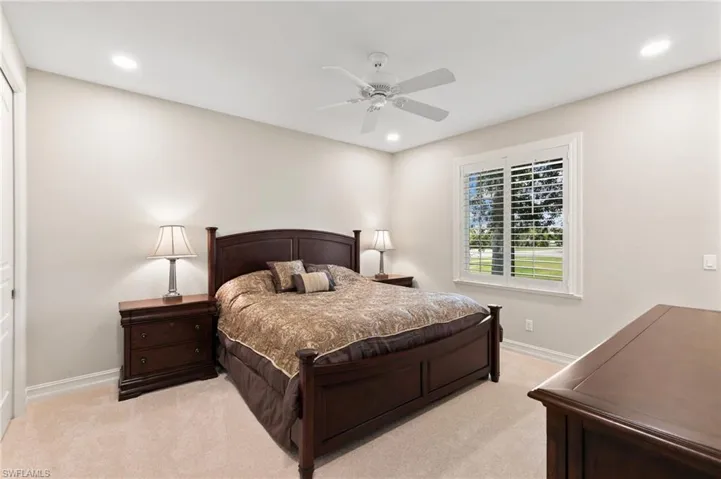 Carpeted bedroom with ceiling fan and a closet