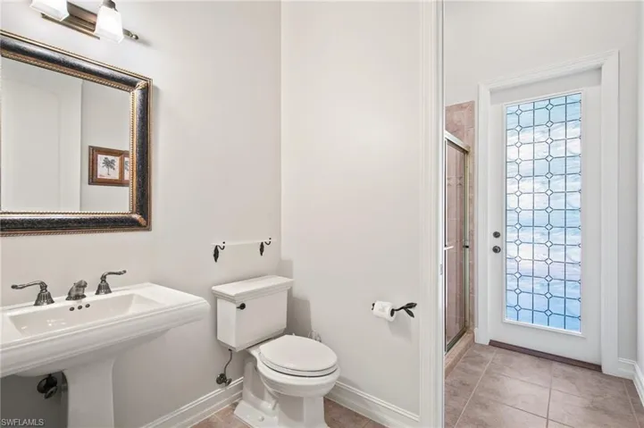 Bathroom with toilet, sink, tile patterned floors, and a shower with shower door