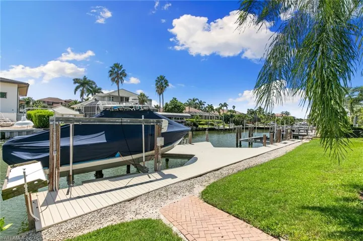 View of dock with a lawn and a water view