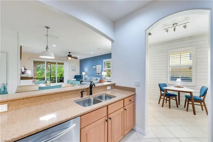 Kitchen with hanging light fixtures, dishwasher, ceiling fan, wooden walls, and sink