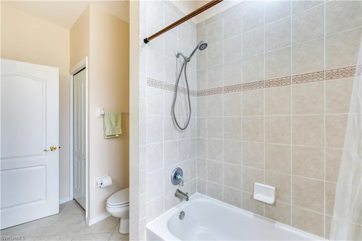 Bathroom with shower / tub combo with curtain, toilet, and tile patterned floors
