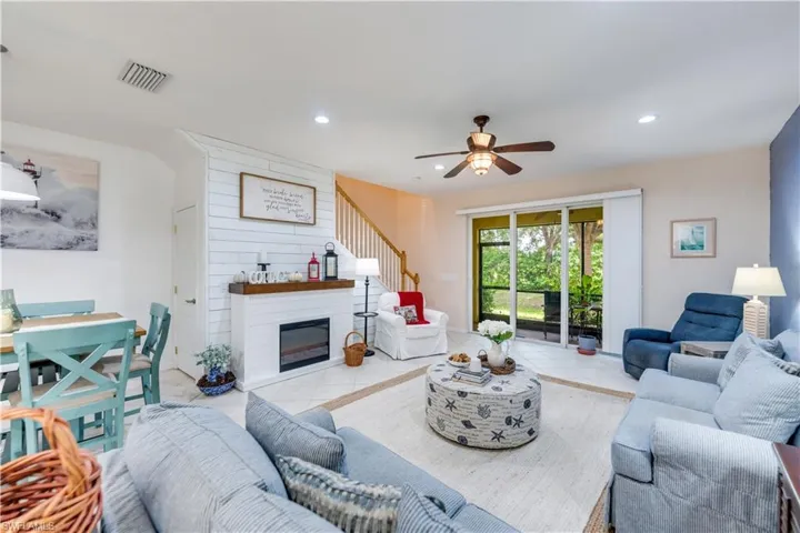 Living room with ceiling fan, light tile patterned floors, and a large fireplace