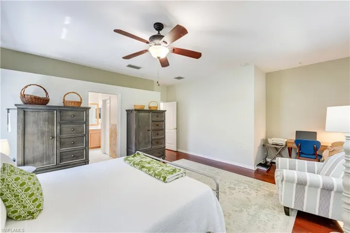 Bedroom featuring ceiling fan, dark wood-type flooring, and ensuite bathroom