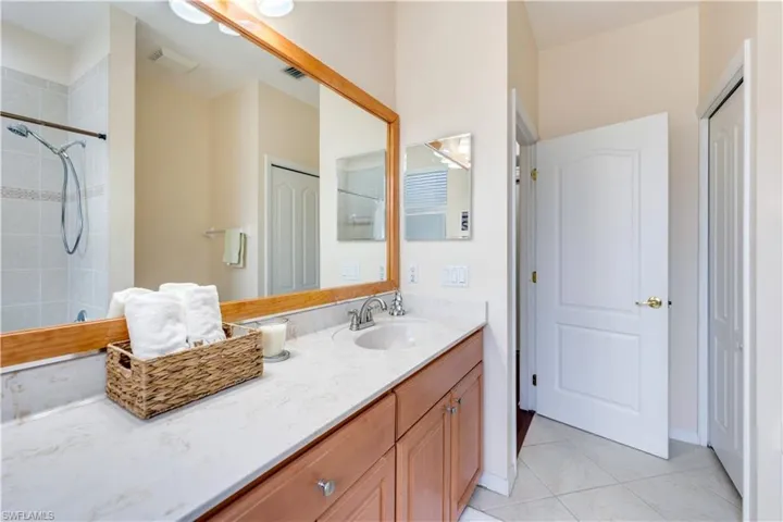 Bathroom with a tile shower, tile patterned flooring, and vanity