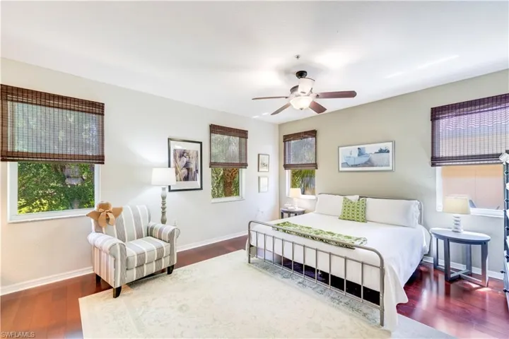 Bedroom with multiple windows, ceiling fan, and dark wood-type flooring