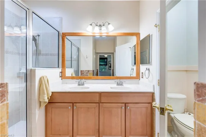 Bathroom with an enclosed shower, vanity, and toilet