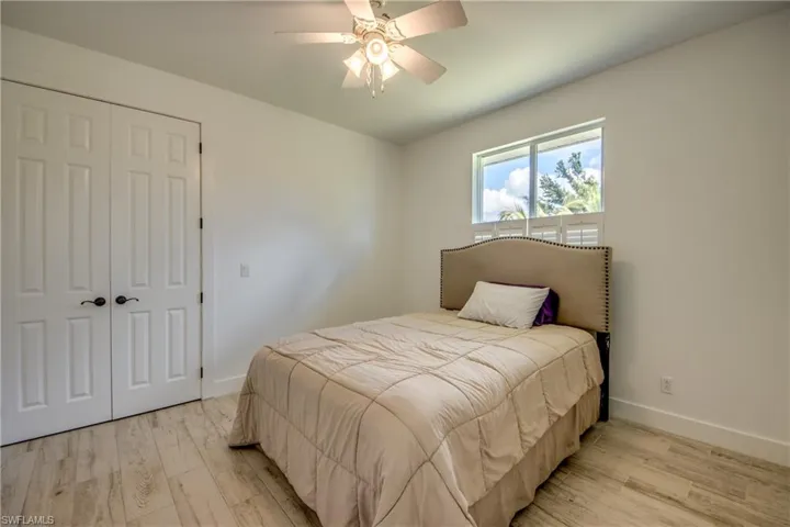 Bedroom with a closet, light wood colored tile  flooring, and ceiling fan