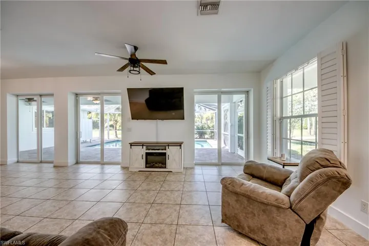 Living room with ceiling fan, a wealth of natural light, and light tile floors