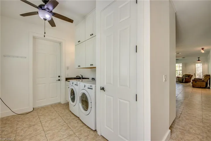 laundry room with wash basin featuring washing machine and dryer, ceiling fan, pantry cabinets, and light tile floors