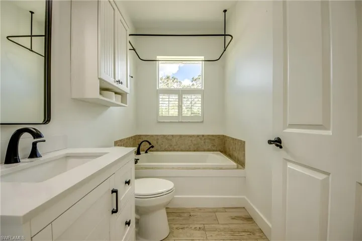 Bathroom featuring hardwood / wood-style tile  flooring, vanity, toilet, and a bathing tub