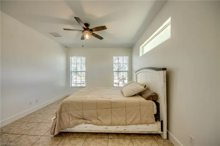 Bedroom featuring ceiling fan, light tile flooring, and multiple windows