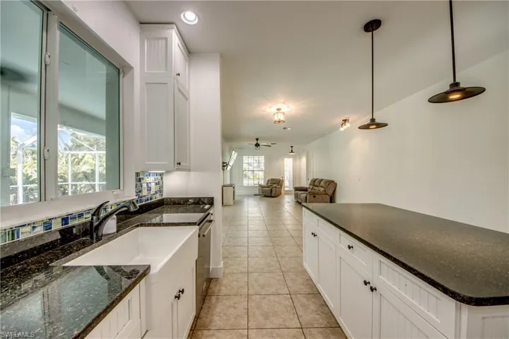 Kitchen with white cabinetry, light tile flooring, ceiling fan, and pendant lighting