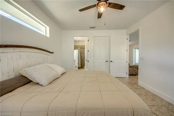Bedroom with ceiling fan and light tile flooring