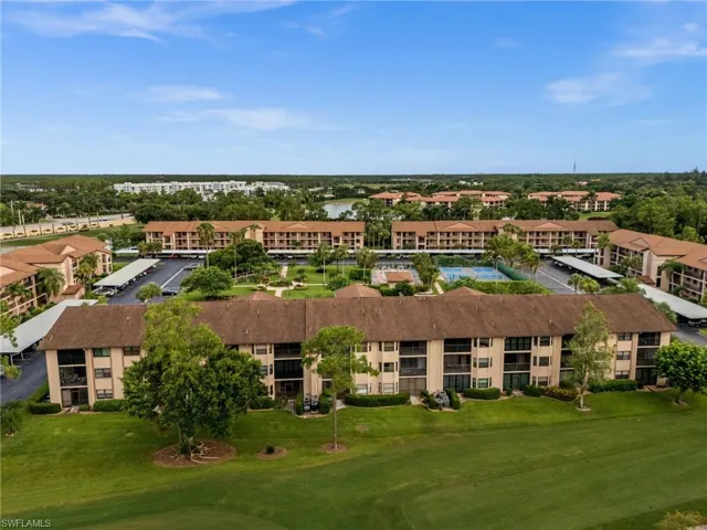 Community featuring multiple multi-story residential buildings, ample green spaces, and covered parking areas