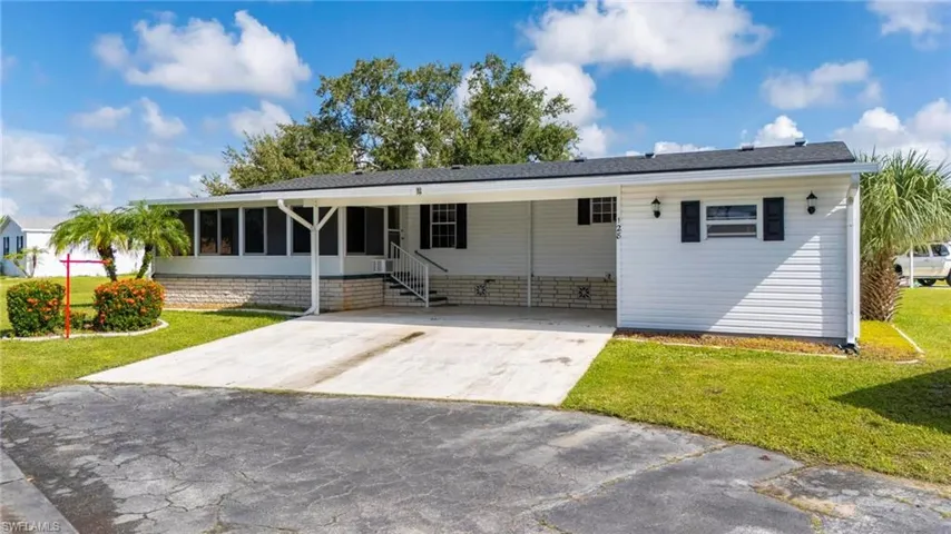 View of front of property featuring a front yard, driveway, and a carport