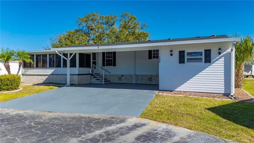 View of front of home featuring a front lawn, a carport, driveway, and a sunroom