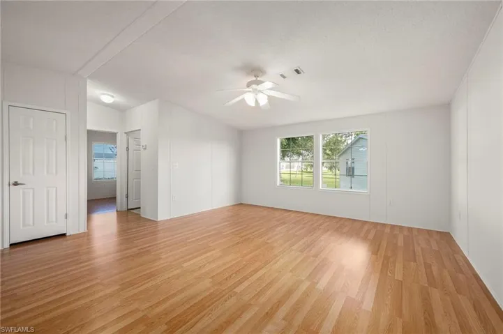 Empty room with plenty of natural light, light wood-style floors, a textured ceiling, and ceiling fan