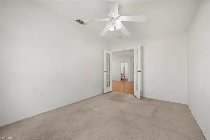 Unfurnished bedroom featuring carpet flooring, a ceiling fan, and french doors
