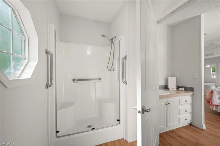 Ensuite bathroom with light wood-type flooring, vanity, and a shower stall