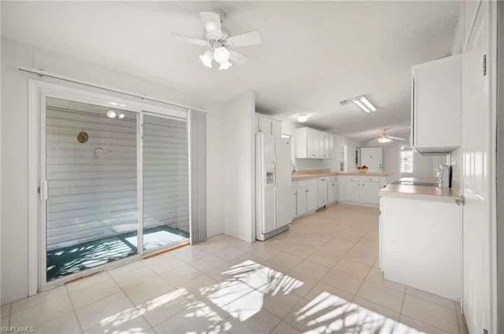 Kitchen with a ceiling fan, light countertops, white cabinetry, white appliances, and light tile patterned floors