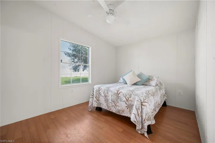 Bedroom with wood-type flooring, ceiling fan, and a decorative wall