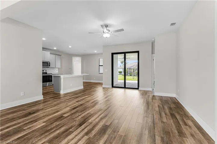 Spare room featuring dark wood-style flooring and baseboards