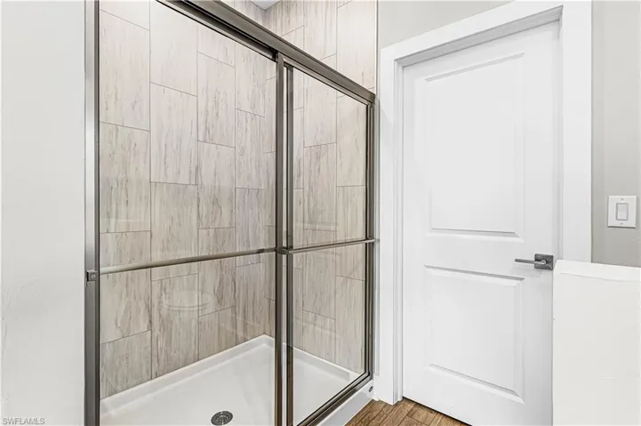 Bathroom with a shower stall, double vanity, and dark wood finished floors
