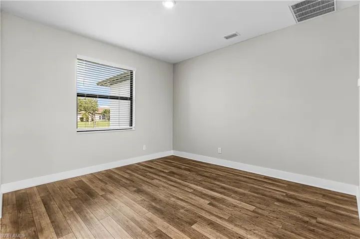 Kitchen with gray cabinets, appliances with stainless steel finishes, light stone counters, light wood finished floors, and recessed lighting