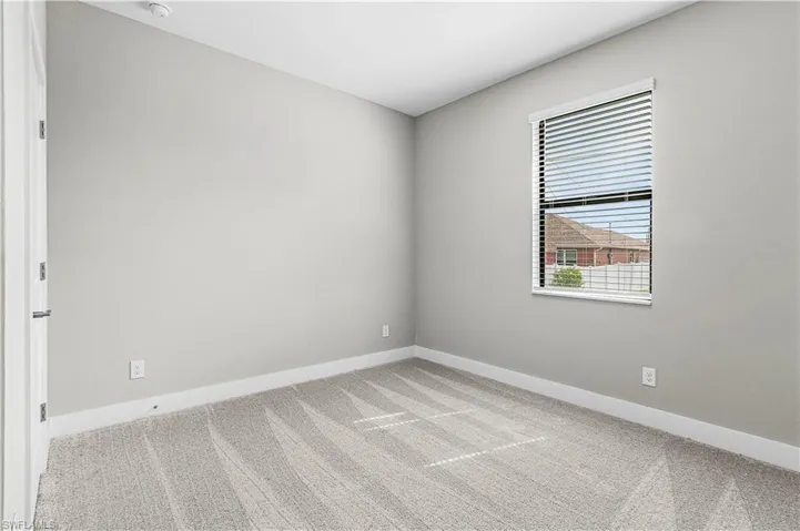 Unfurnished bedroom with light colored carpet and baseboards