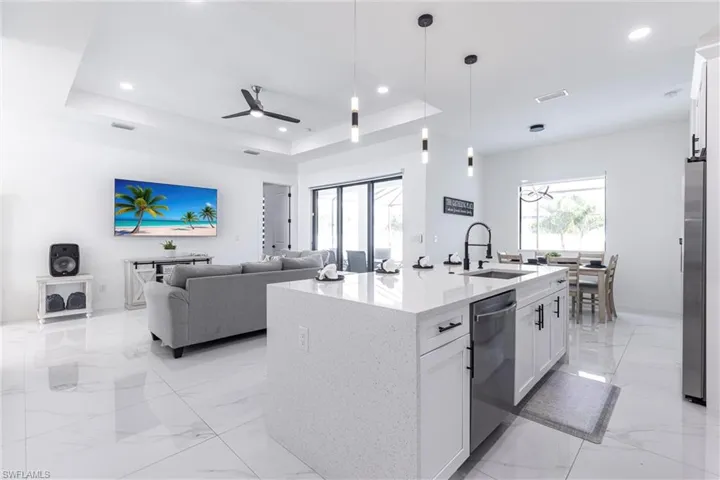 Kitchen featuring white cabinets, a tray ceiling, light quartz countertops, hanging light fixtures, and recessed lighting