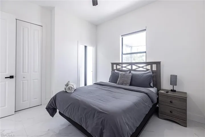 Bedroom with light marble finish flooring, ceiling fan, and a closet