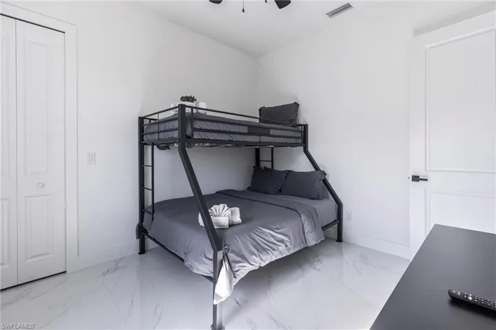 Bedroom with a ceiling fan and light marble finish flooring