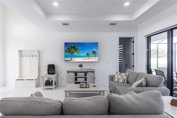 Living area featuring a raised ceiling and recessed lighting