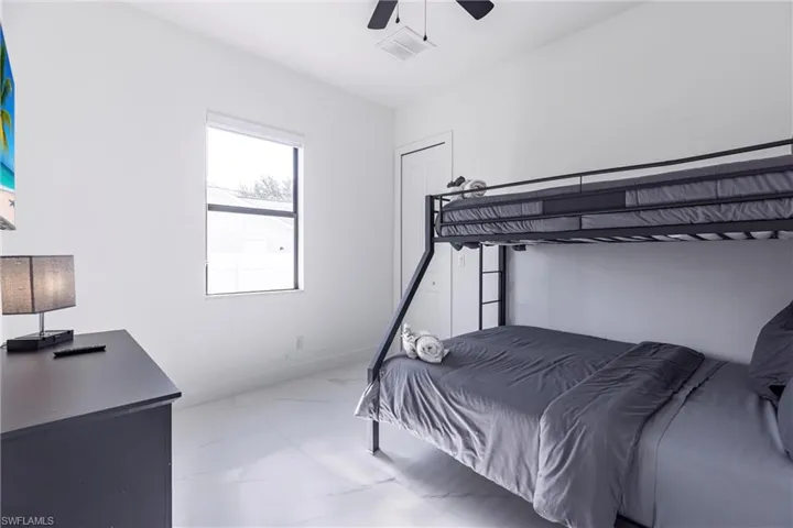 Bedroom with a ceiling fan and marble look tile flooring