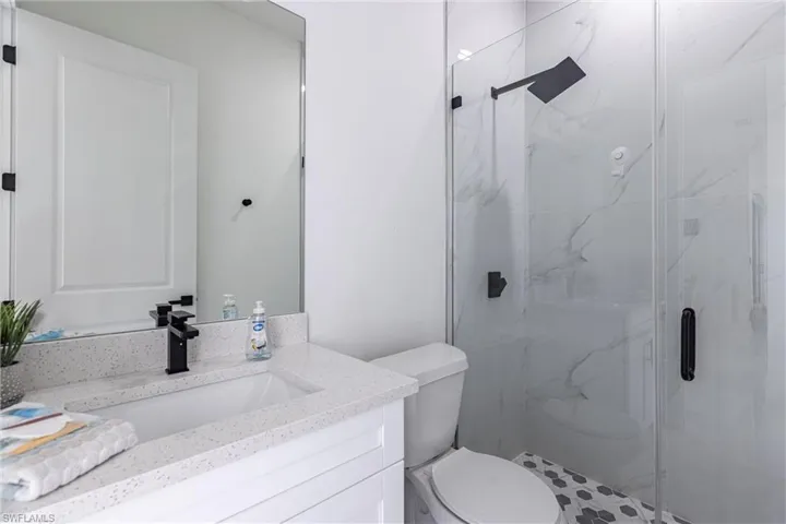 Bathroom with quartz vanity and a marble finish shower